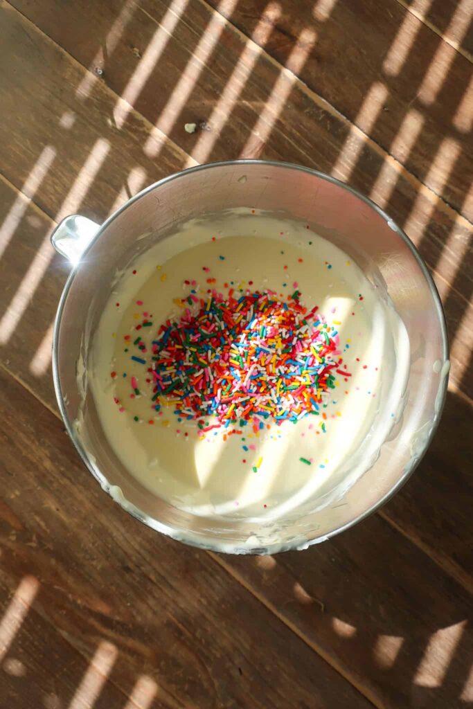 vanilla cheesecake batter with sprinkles in mixing bowl