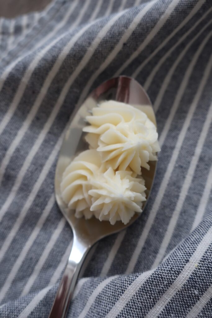 vanilla buttercream frosting on spoon sitting on blue striped napkin