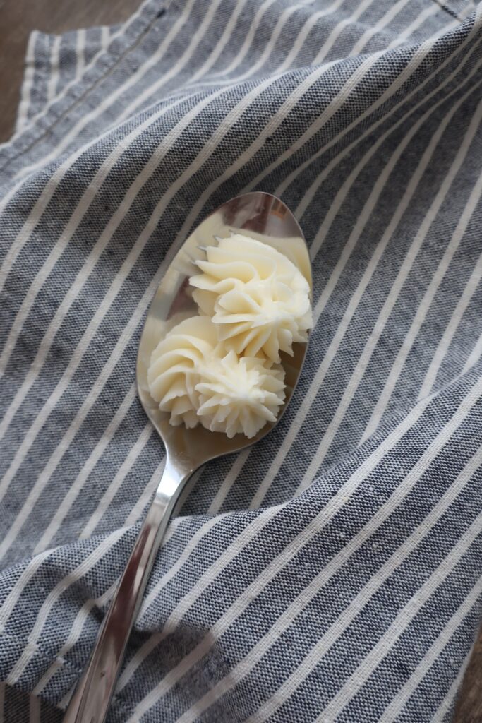 vanilla buttercream frosting on spoon sitting on blue striped napkin