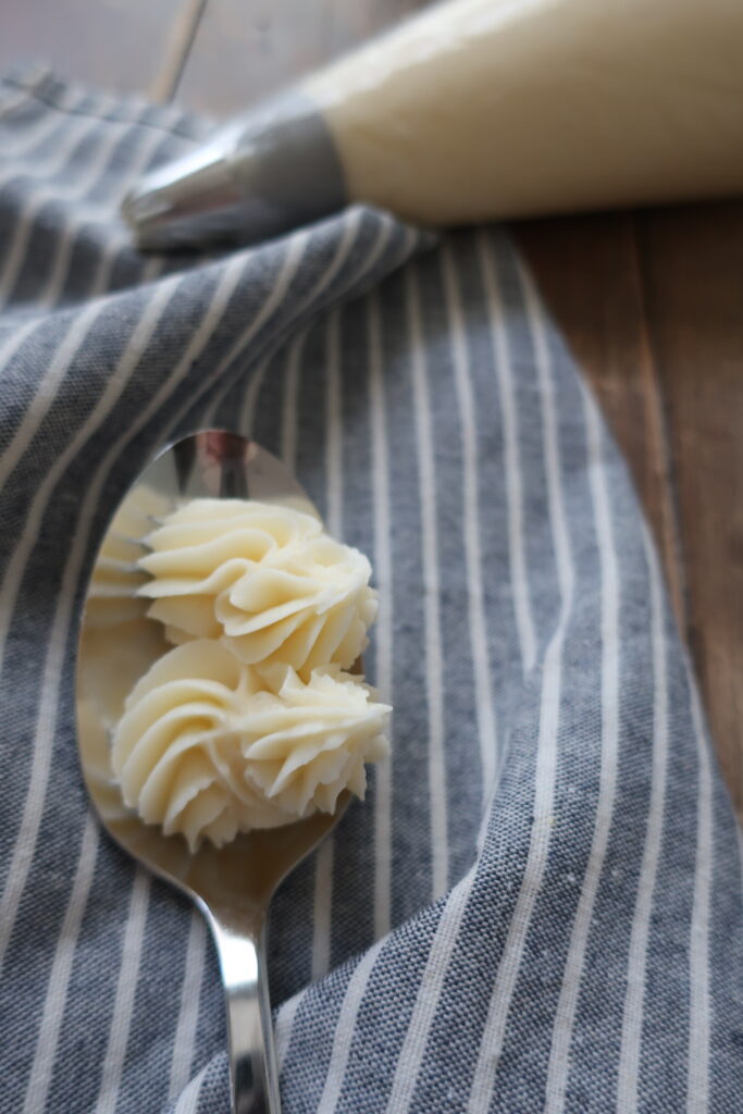 vanilla buttercream frosting on spoon sitting on blue striped napkin