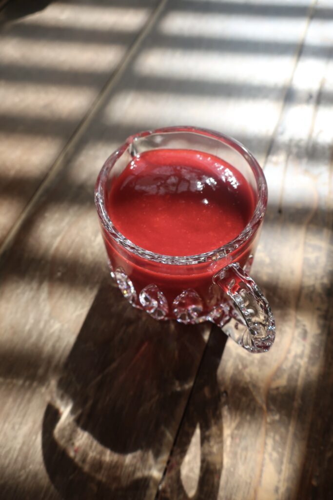 homemade raspberry sauce in small glass pitcher