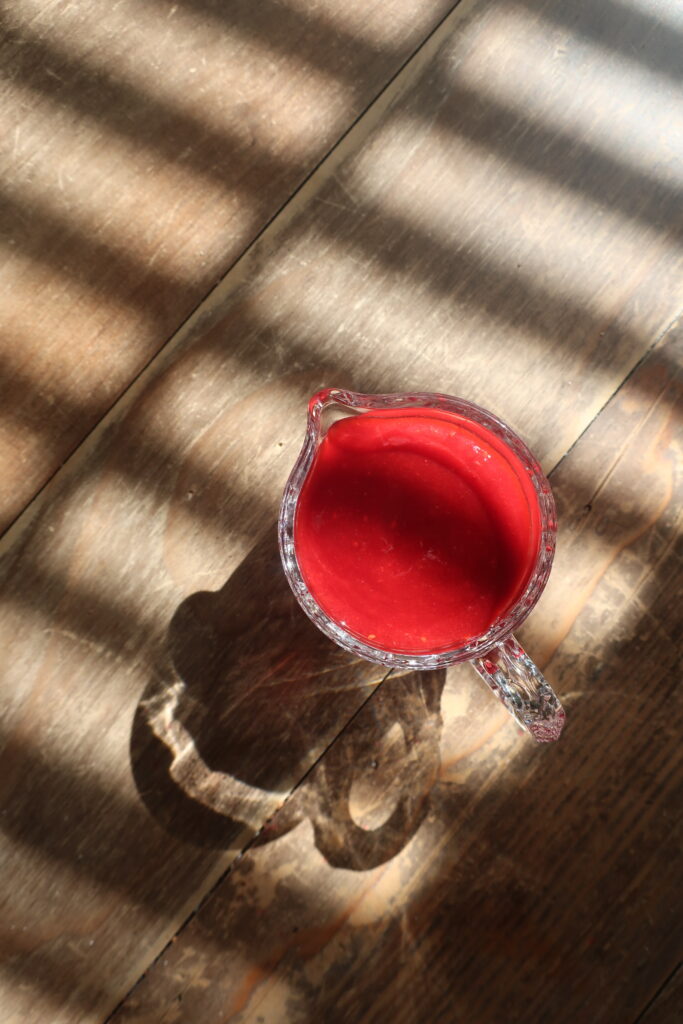 homemade raspberry sauce in small glass pitcher