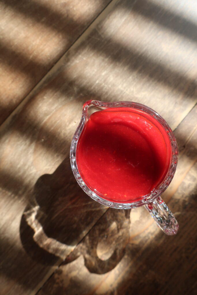 homemade raspberry sauce in small glass pitcher