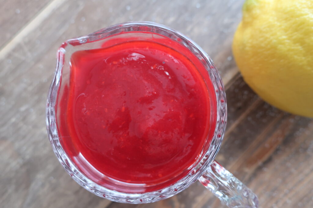 homemade raspberry sauce in small glass pitcher