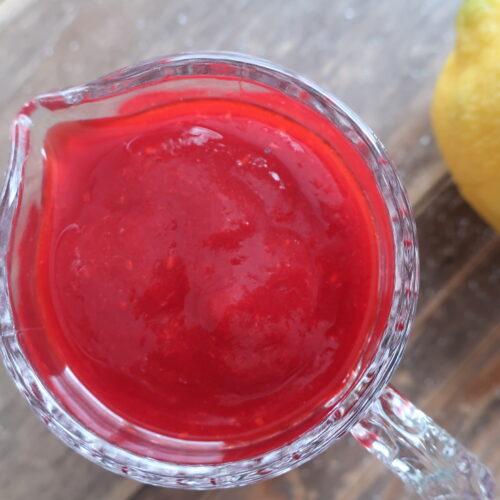 homemade raspberry sauce in small glass pitcher