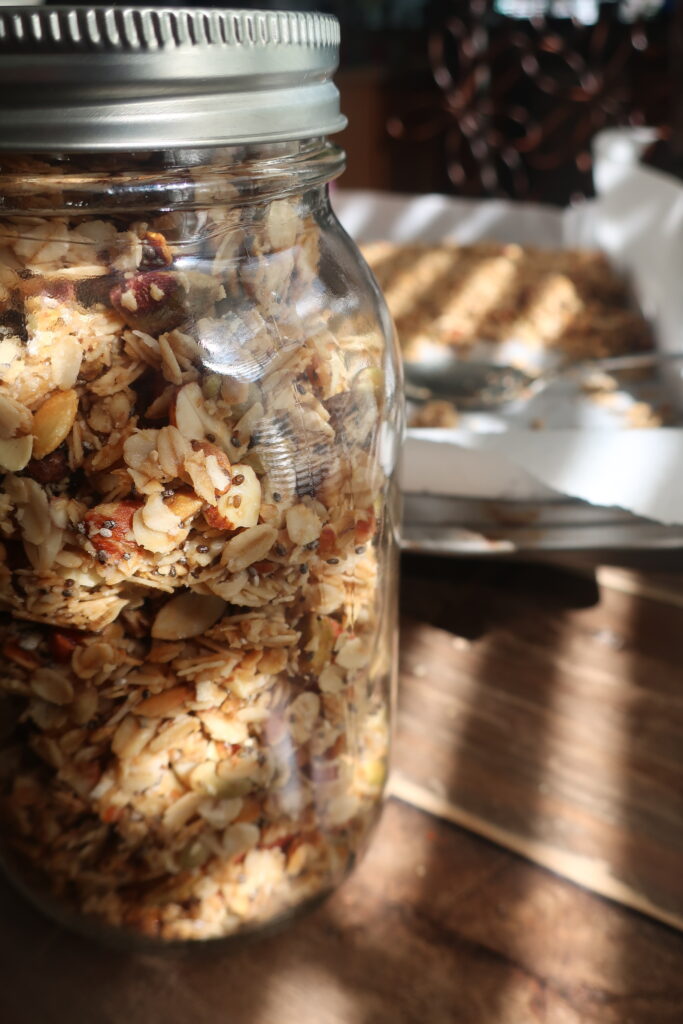 mason jar filled with homemade granola; granola with oats, chia seeds, coconut flakes, almonds, pepitas, pistachios