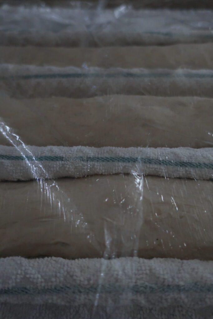 three French baguettes doing their final rise in a couche made with a kitchen towel