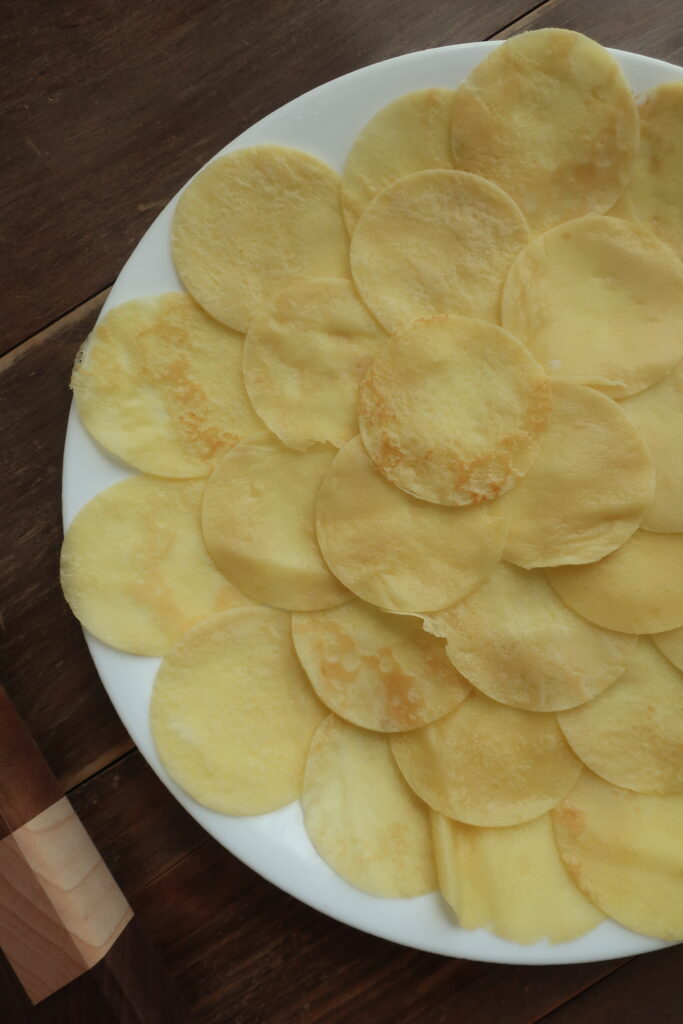 cutting out circles for mini crepe stacks; mini crepes formed into stacks layered with homemade raspberry sauce, homemade lemon curd, and homemade whipped cream, and dusted with powdered sugar