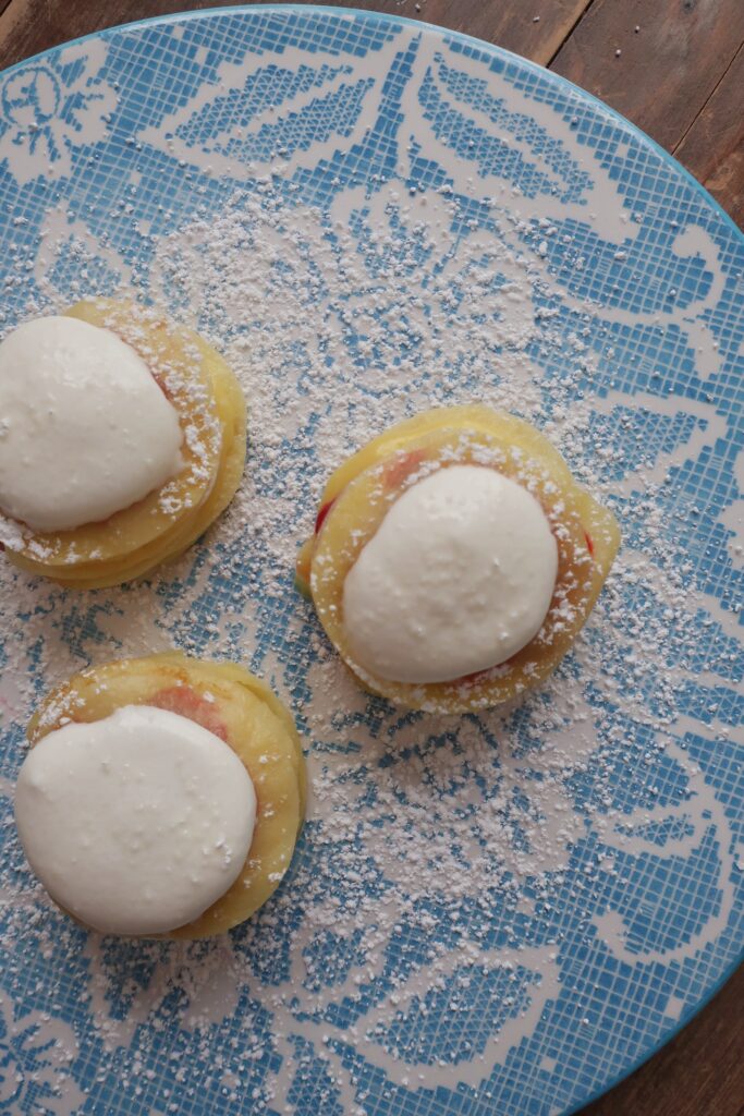 mini crepes formed into stacks layered with homemade raspberry sauce, homemade lemon curd, and homemade whipped cream, and dusted with powdered sugar