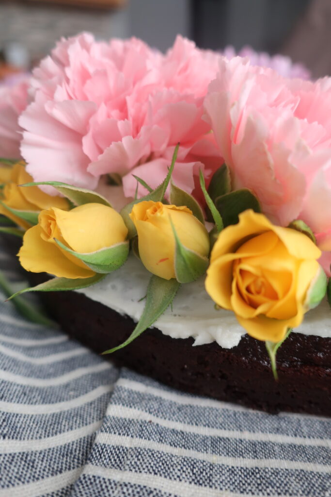 flowers for spring bunny cake; chocolate cake with vanilla buttercream frosting topped with fresh pink, purple, and yellow flowers, shaped like a bunny; bunny cake for easter; easter dessert