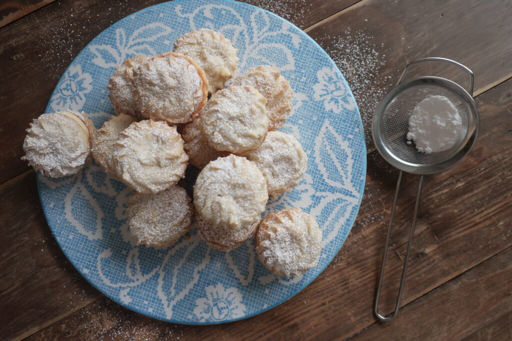 viennese whirl sandwich cookies with passionfruit buttercream dusted with powdered sugar