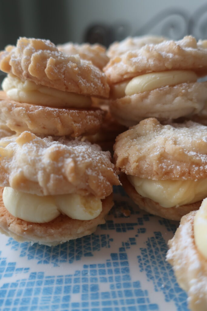 viennese whirl sandwich cookies with passionfruit buttercream dusted with powdered sugar