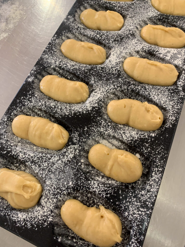 batter for lemon madeleines piped into floured madeleine baking mold; lemon madeleines with lemon glaze