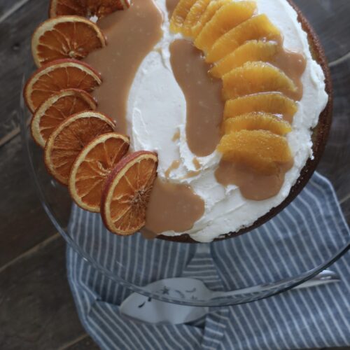 orange olive oil cake topped with brown butter cream cheese frosting, homemade caramel sauce, and dehydrated oranges