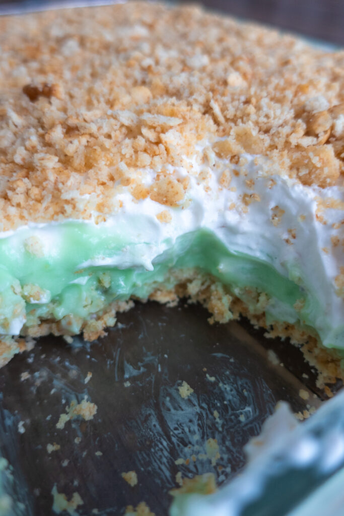 inside look at no bake pistachio dessert with pistachio pudding, cool whip, and crushed ritz crackers