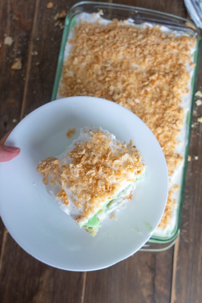 slice of no bake pistachio dessert with pistachio pudding, cool whip, and crushed ritz crackers