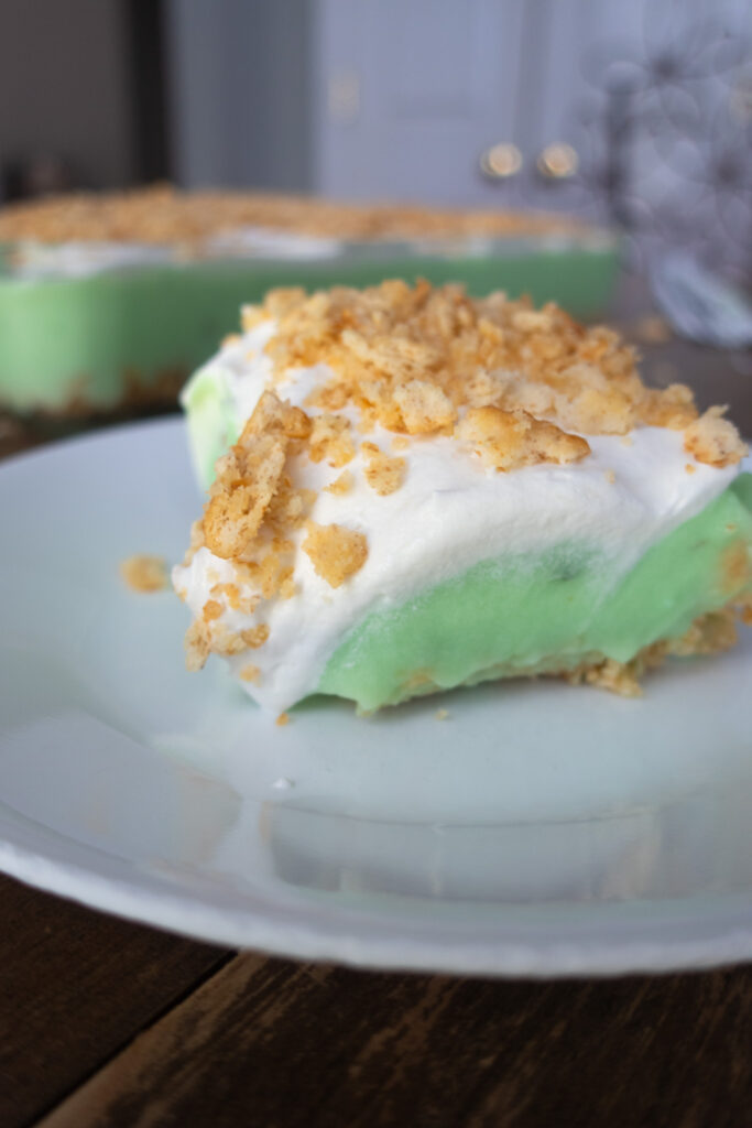 slice of no bake pistachio dessert with pistachio pudding, cool whip, and crushed ritz crackers