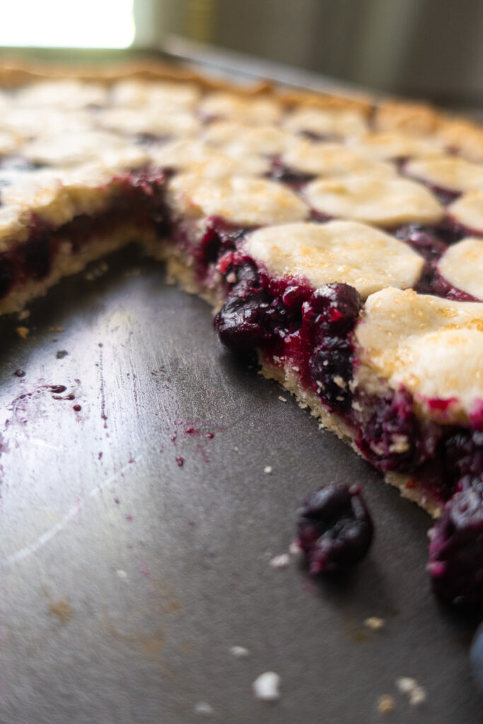 inside look at blueberry tart in baking sheet next to blue striped napkin