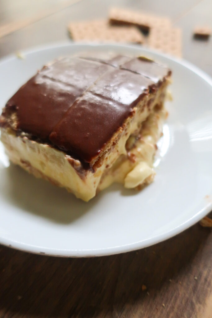 no bake chocolate eclair cake with french vanilla cream layered with graham crackers and topped with chocolate