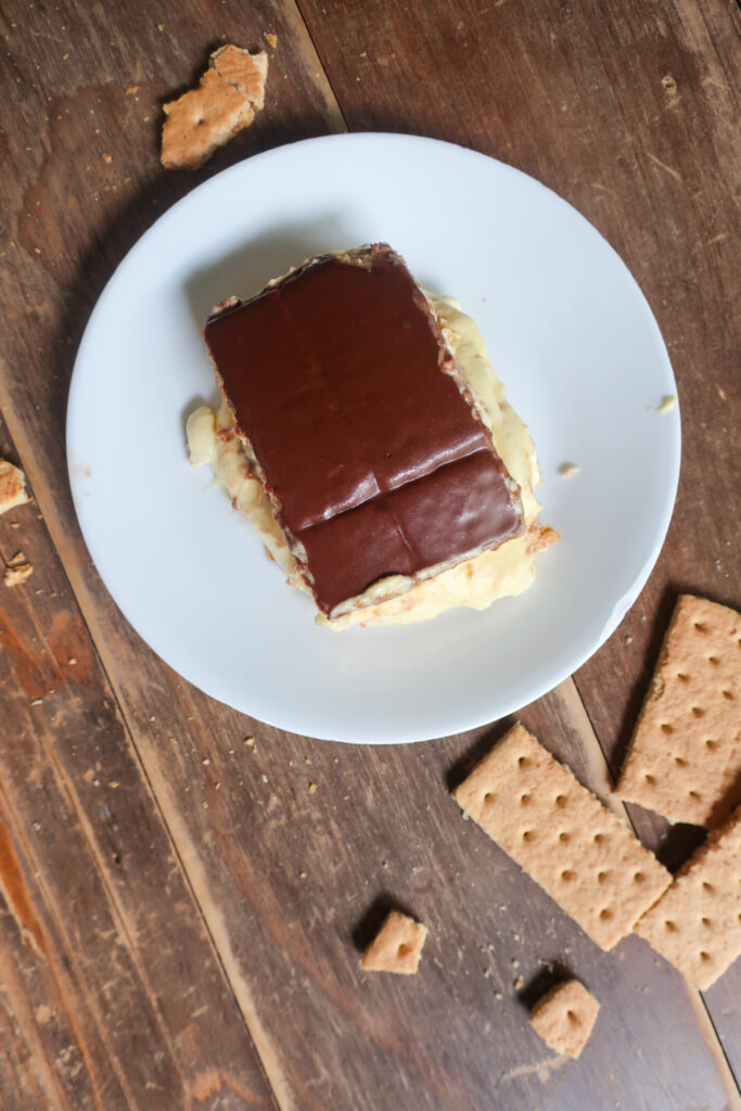 no bake chocolate eclair cake with french vanilla cream layered with graham crackers and topped with chocolate