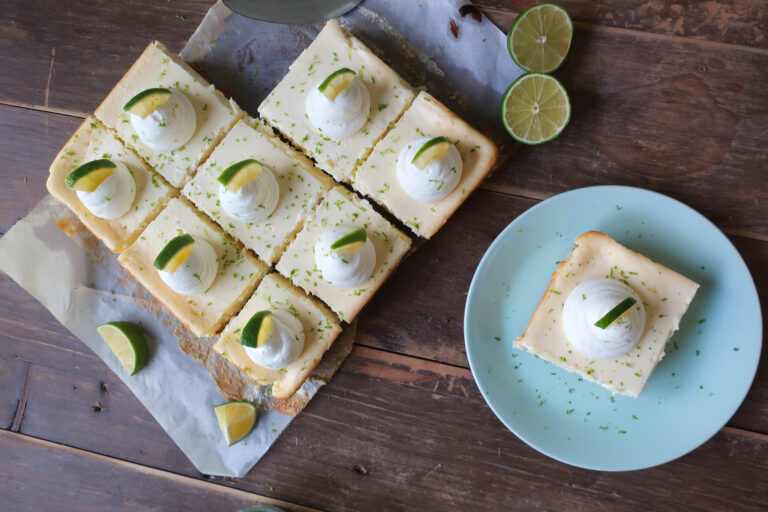 key lime cheesecake bars with graham cracker crust and topped with fresh whipped cream