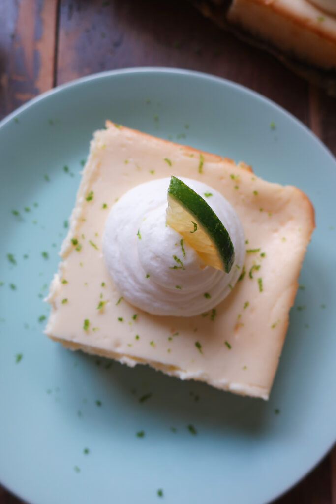 key lime cheesecake bars with graham cracker crust and topped with fresh whipped cream