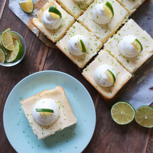 key lime cheesecake bars with graham cracker crust and topped with fresh whipped cream