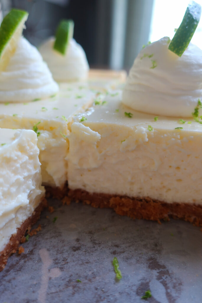 inside look at key lime cheesecake bars with graham cracker crust and topped with fresh whipped cream