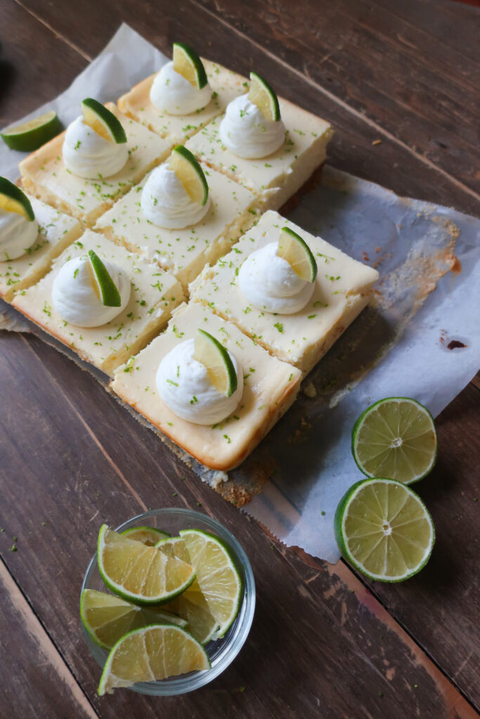 key lime cheesecake bars with graham cracker crust and topped with fresh whipped cream