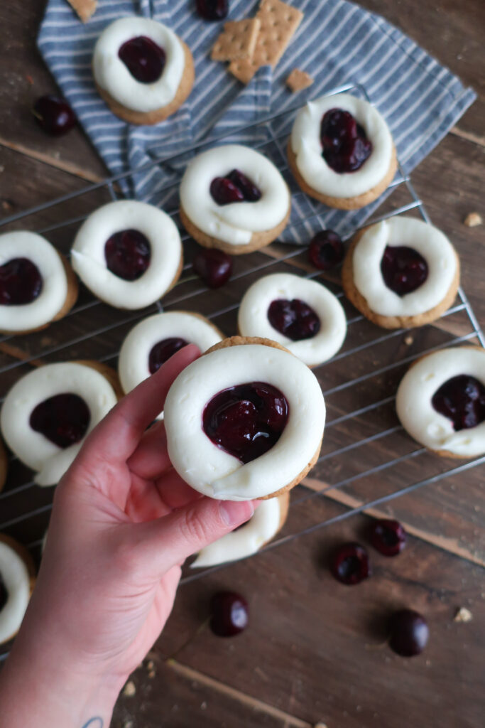 up close shot of cherry cheesecake cookies; cream cheese frosting; cherry pie filling; graham cracker cookies