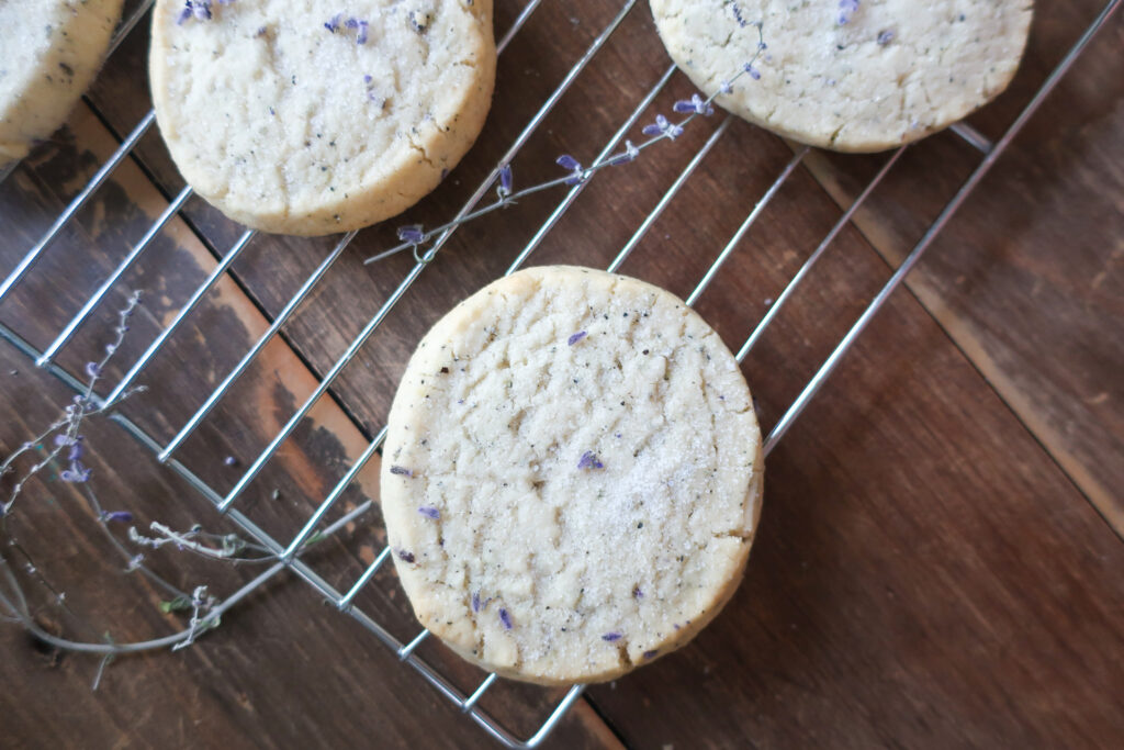 earl grey and lavender shortbread cookies on wire rack next to pitcher of fresh lavender and metal spatula