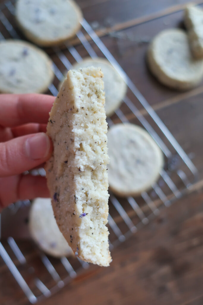 inside of earl grey and lavender shortbread cookies on wire rack next to pitcher of fresh lavender and metal spatula