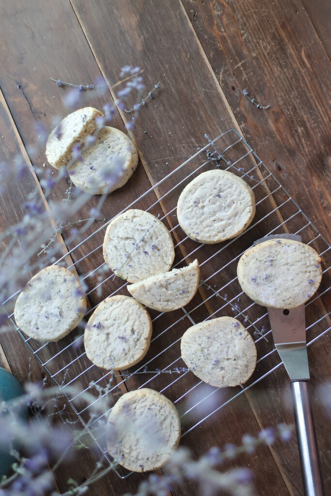 earl grey and lavender shortbread cookies on wire rack next to pitcher of fresh lavender and metal spatula