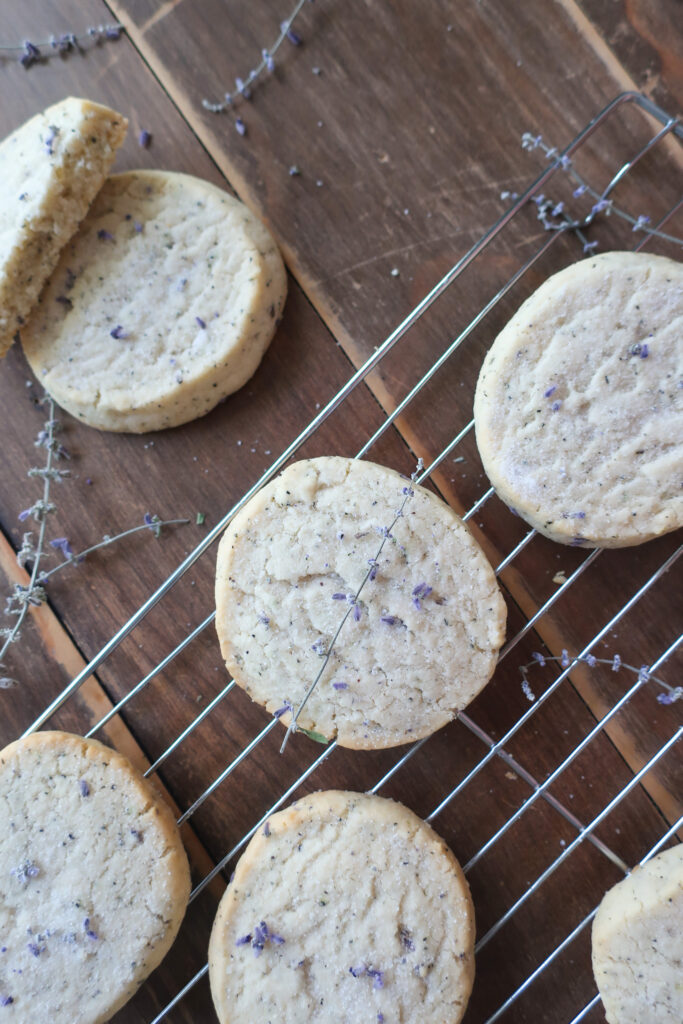 earl grey and lavender shortbread cookies on wire rack next to pitcher of fresh lavender and metal spatula