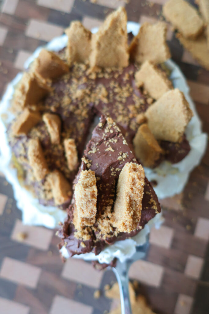 close up slice of s'mores pavlova with french meringue, dark chocolate ganache, and graham cracker crust topping