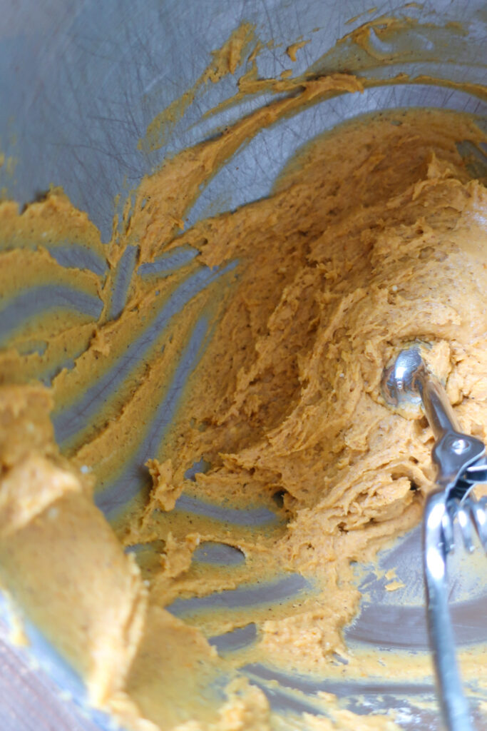 Batter with cookie scoop inside for grandma's soft pumpkin cookies with simple glaze