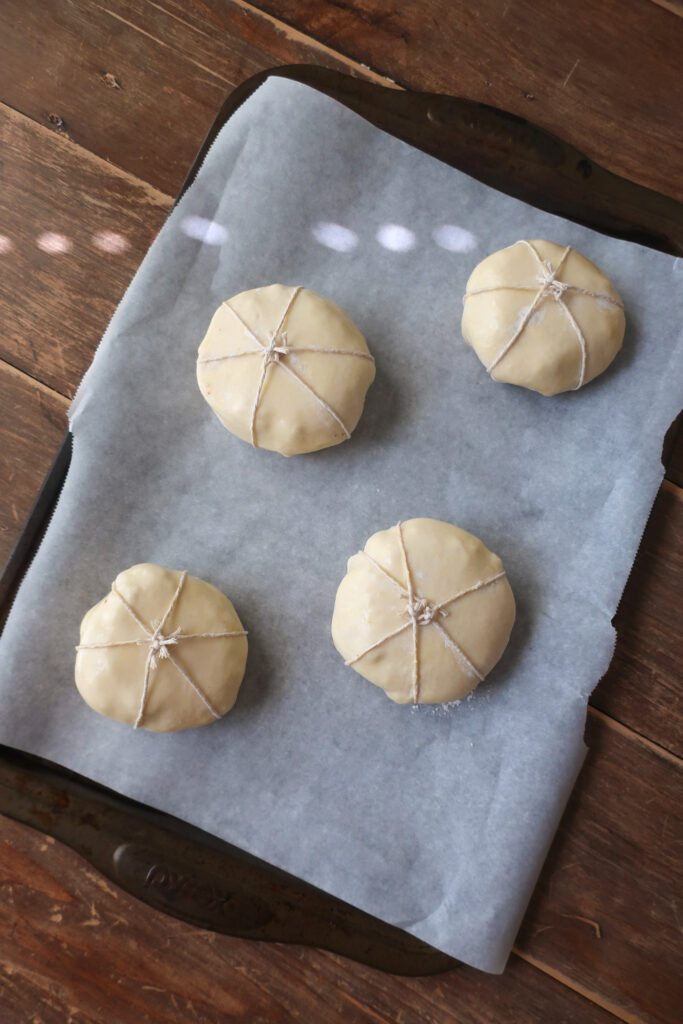 wrapped and unbaked apple puff pastry shaped like pumpkins with basil leaves for pumpkin stems