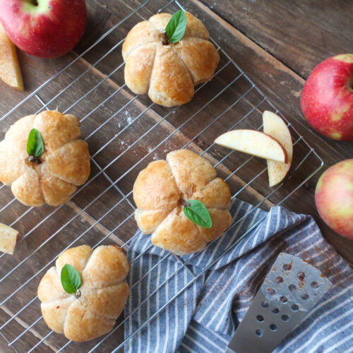 multiple apple puff pastry shaped like pumpkins with basil leaves for pumpkin stems