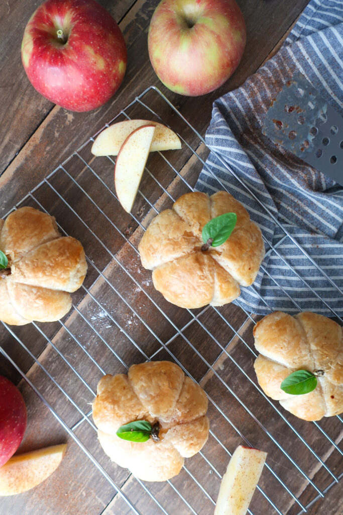 multiple apple puff pastry shaped like pumpkins with basil leaves for pumpkin stems