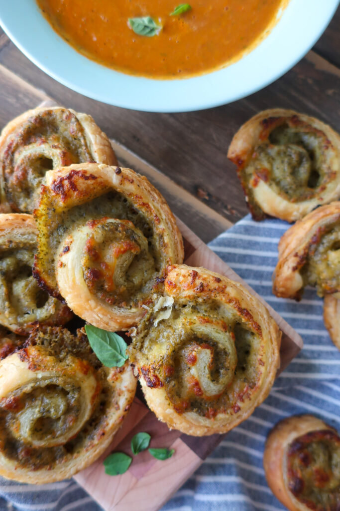 pesto pinwheels made with puff pastry next to a bowl of tomato soup