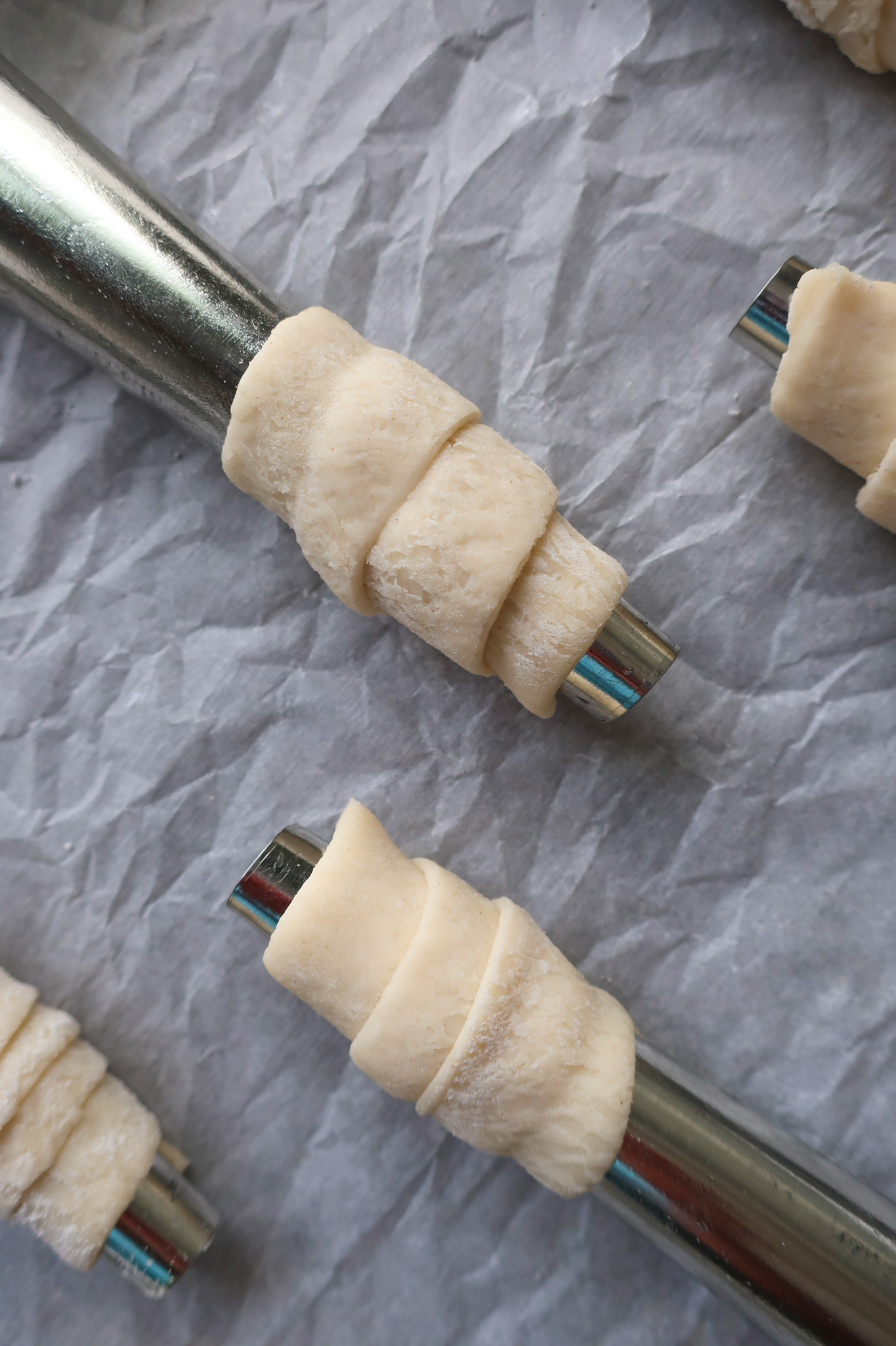 raw puff pastry wrapped on dowel rods for lady lock puff pastry filled with cream frosting