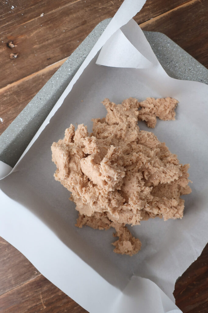 cookie dough in pan for snickerdoodle bars with brown butter cinnamon frosting