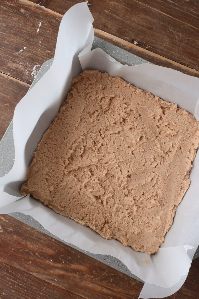 cookie dough in pan for snickerdoodle bars with brown butter cinnamon frosting