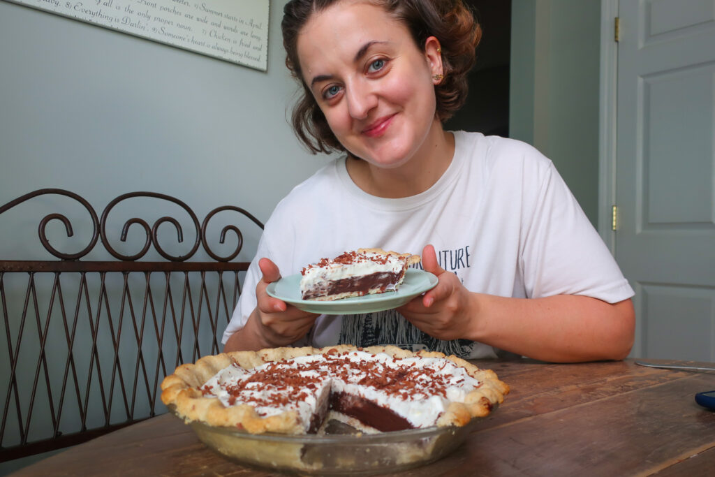 woman with a piece of chocolate pudding pie with whipped cream topping