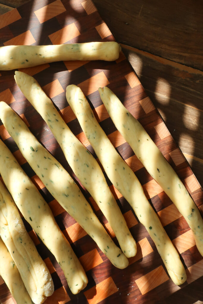 dough of rosemary challah rolls cut and rolled into cylinders before forming into rolls