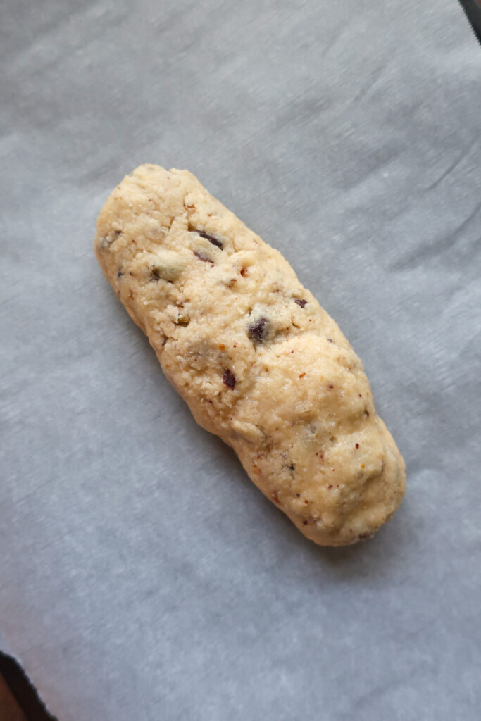 Pistachio and dark chocolate biscotti dough formed into a log