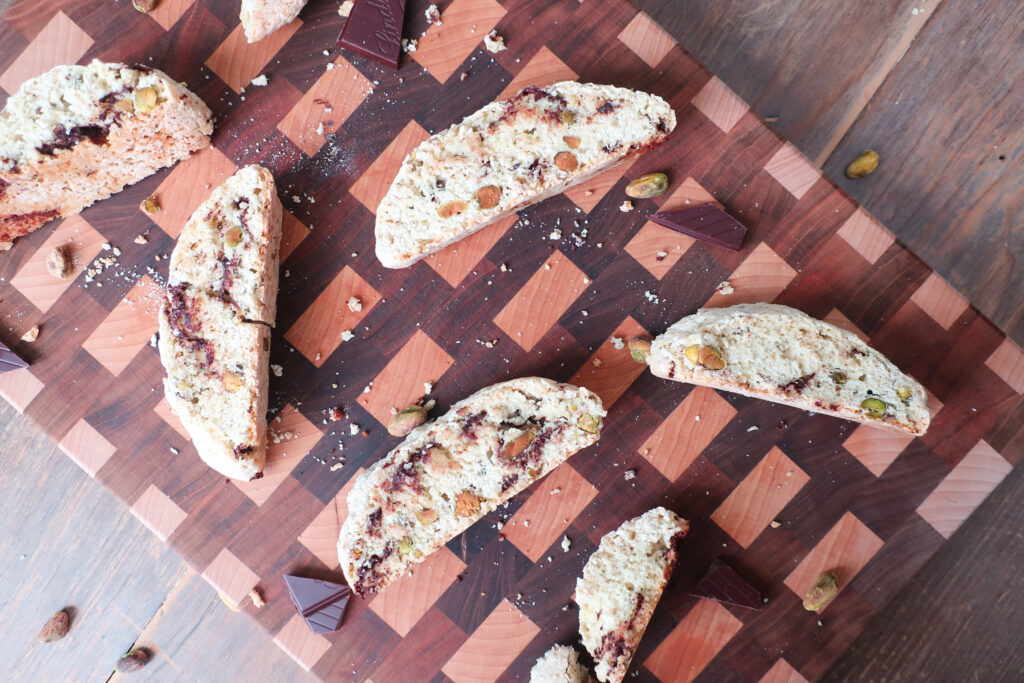 Pistachio and dark chocolate biscotti sliced showing the filling, sitting on a cutting board