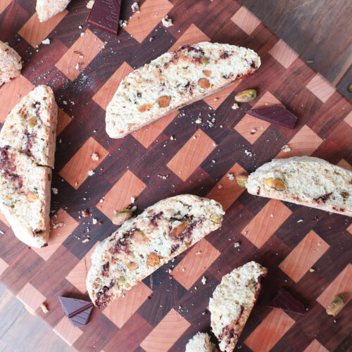 Pistachio and dark chocolate biscotti sliced showing the filling, sitting on a cutting board