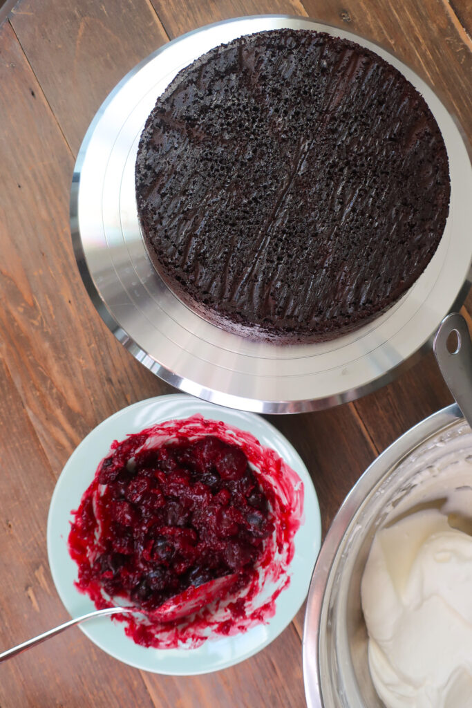 prepped ingredients to make a black forest cake; chocolate cake, cherries, and fresh whipped cream