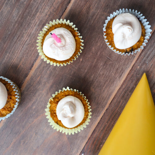 blueberry and pumpkin. pupcakes (dog cupcakes) with peanut butter and greek yogurt frosting; cupcakes sitting on wood table with yellow party hat